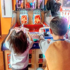 Two kids playing and having fun at Gatti's Pizza franchise with the pizza menu and prices.