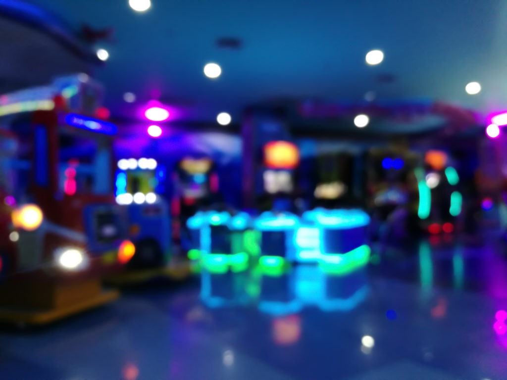 blurred arcade machine game for children game play in department store. Playground with colorful neon lights and bokeh light. Colorful absract background.