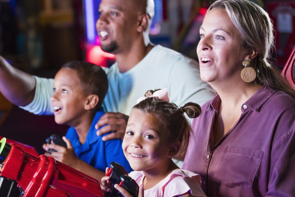 Family bonding while mother, father, and son watch on the screen and are mesmerized by the game in Mr. Gatti's Pizza Franchise with the family entertainment center and fun entertainment center.