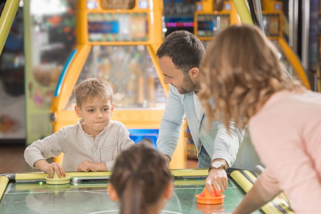 Happy family with two kids playing air hockey together in Mr. Gatti's Pizza Franchise with the arcade games and ordering system.